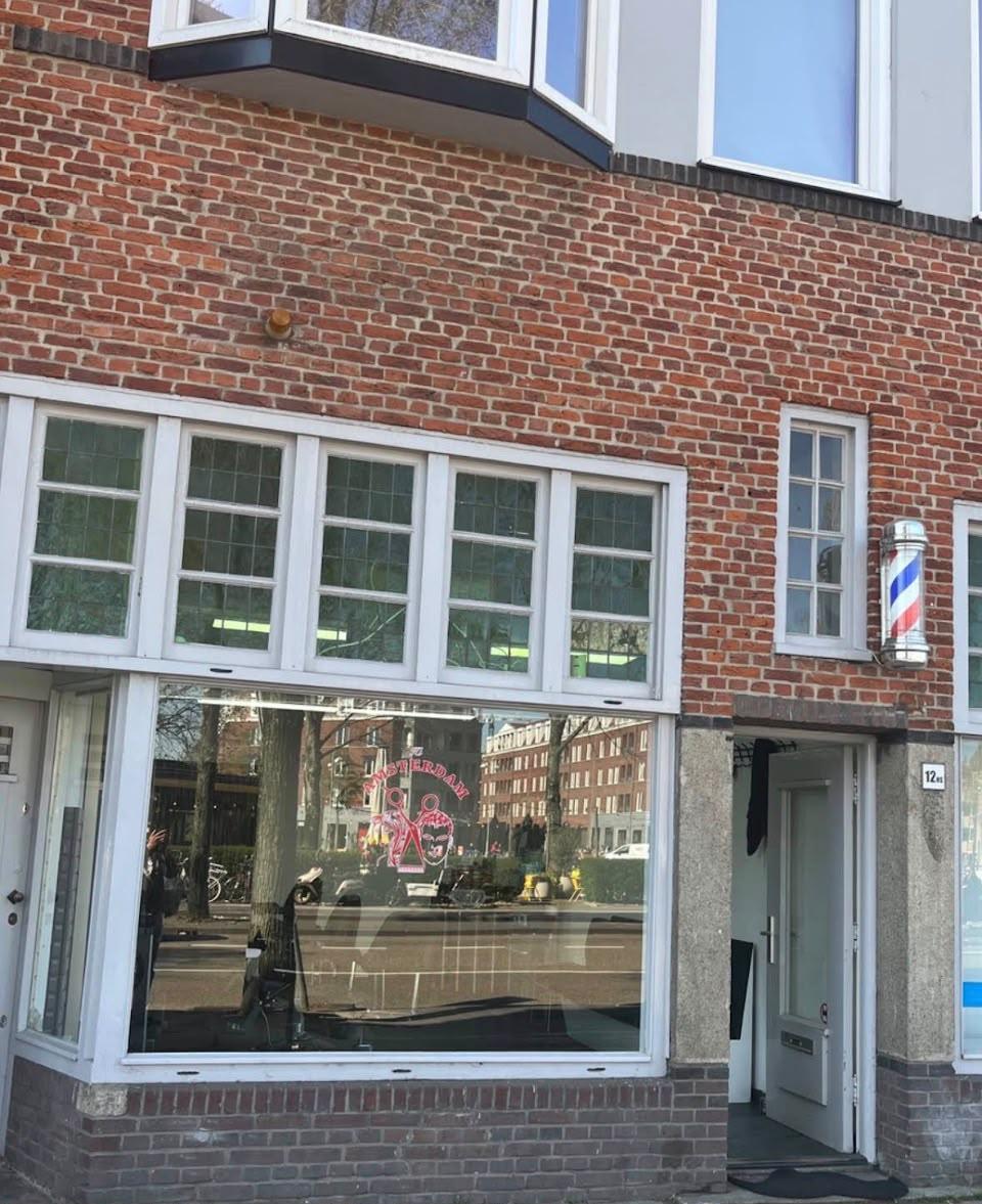 De gevel van de salon aan de Zeeburgerstraat, met barberspaal naast de deur